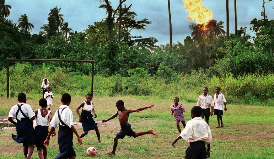 390464 19: Children in the Nigerian village of Akaraolu play soccer at recess while the nearby Oshie gas flare roars on. No one under the age of 30 in the village can remember a time before what they  ...