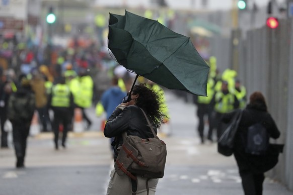 A woman&#039;s unbrella is turned inside out by a gust of wind outside the venue for the COP26 U.N. Climate Summit in Glasgow, Scotland, Friday, Nov. 12, 2021. (AP Photo/Scott Heppell)