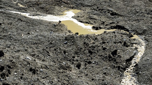 epa12144827 Water from the Lonza river flows over the mud and stone, after the formation of a lake on the last houses of the village of Blatten, Switzerland, 30 May 2025. A large part of the Blatten v ...