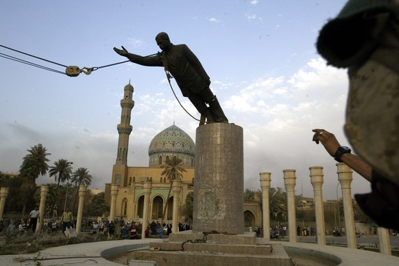 A U.S. marine watches a statue of Saddam Hussein being toppled in Firdaus Square, in downtown Bagdhad in this April 9, 2003 photo. A car bomb destroyed a hotel in central Baghdad on Wednesday night, M ...