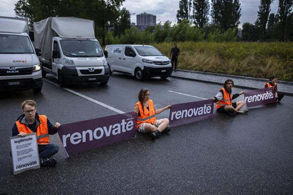 Environmental activists of Renovate Switzerland sit down on the road during a roadblock action on the motorway A1 exit in Zuerich, Switzerland on June 19, 2023. (KEYSTONE/Michael Buholzer).