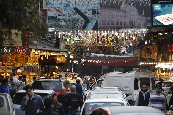 A busy downtown market is seen in Damascus, Syria, on the first day of Ramadan, Islamic holy month, Saturday, April 2, 2022. On the top is a poster showing Syrian President Bashar Assad. (AP Photo/Oma ...