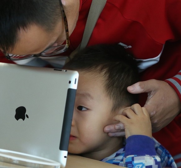 BEIJING, CHINA - OCTOBER 20: A Chinese customer and his son look at the iPad in the newly opened Apple Store in Wangfujing shopping district on October 20, 2012 in Beijing, China. Apple Inc. opened it ...