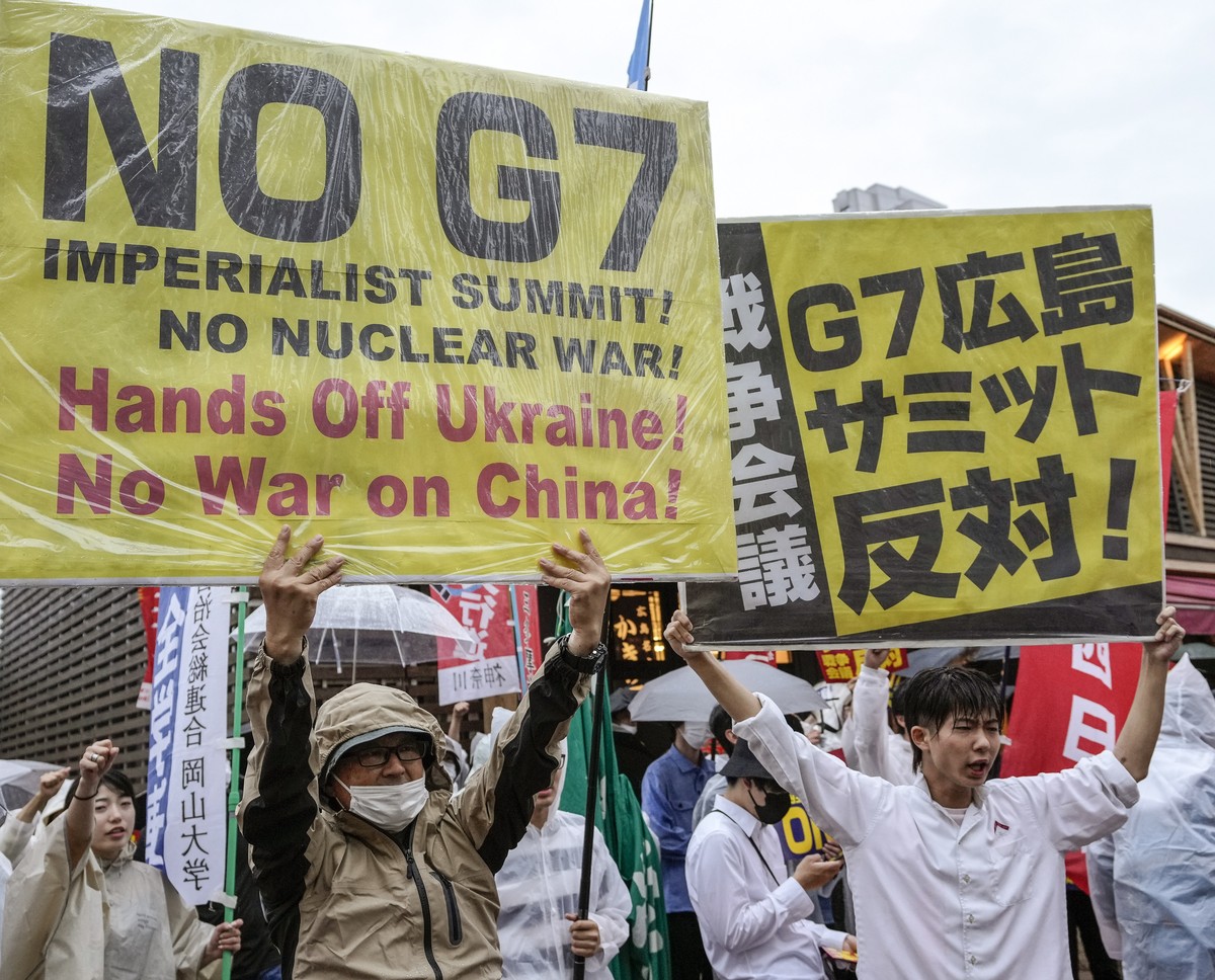epa10636394 Protesters carry placards as they gather near the A-bomb Dome at the Hiroshima Peace Memorial Park, as part of a demonstration against the G7 Hiroshima Summit, ahead of the summit in Hiros ...