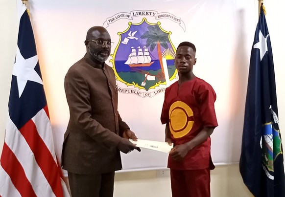 epa09531092 A handout photo made available by the Liberian Presidential Press Office shows Liberian President George Manneh Weah (R) receiving Emmanuel Tuloe, who recently found and returned 50,000 US ...