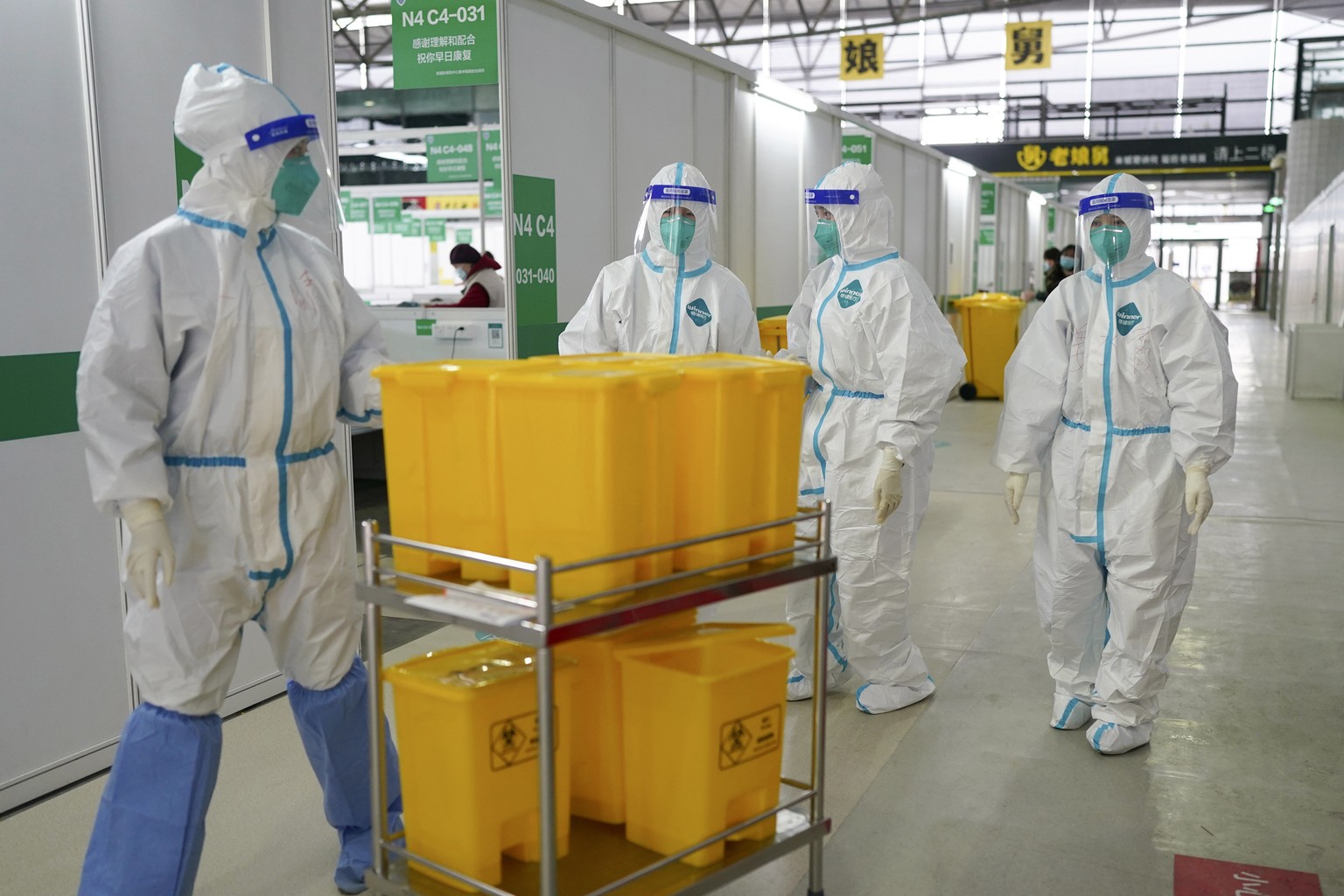 In this photo released by China's Xinhua News Agency, medical workers in protective suits walk at the Shanghai New International Expo Center, which has been converted to a quarantine facility for peop ...