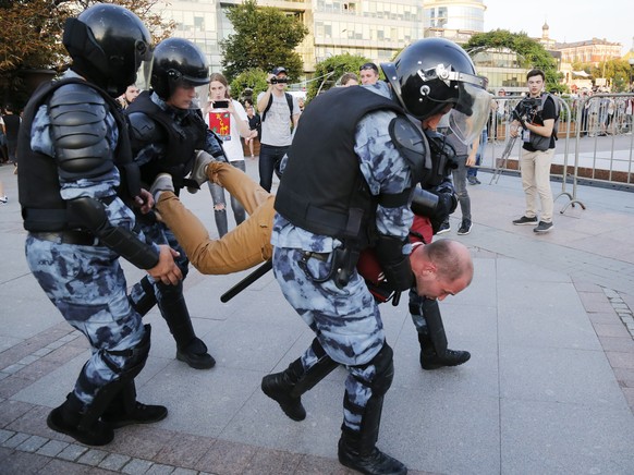 Police officers detain a man during an unsanctioned rally in the centre of Moscow, Russia, Saturday, July 27, 2019. Russian police clashed with demonstrators and have arrested some hundreds in central ...