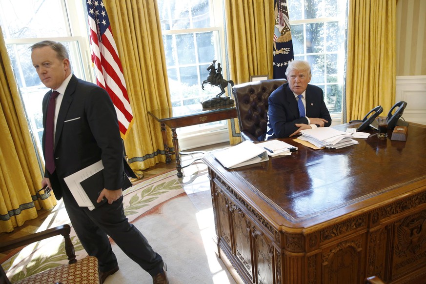 White House Communications Director and spokesman Sean Spicer (L) stands with U.S. President Donald Trump at the conclusion of an interview with Reuters in the Oval Office at the White House in Washin ...