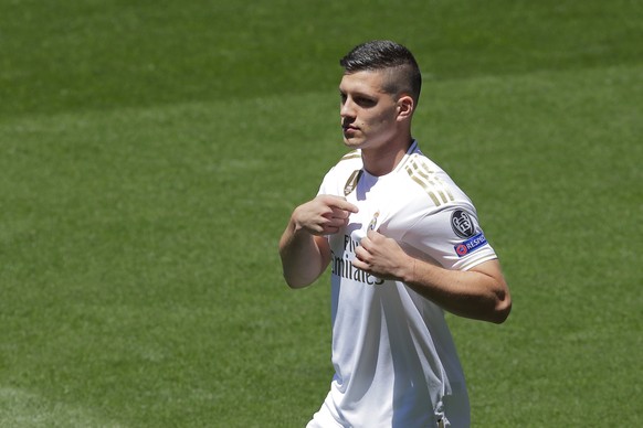 Serbia forward Luka Jovic points to the club emblem on his shirt during his official presentation after signing for Real Madrid at the Santiago Bernabeu stadium in Madrid, Spain, Wednesday, June 12, 2 ...