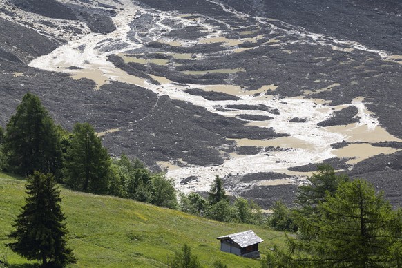 epa12148726 Water from the Lonza river flows over the mud and stone, after the formation of a lake on the last houses of the village of Blatten, Switzerland, 01 June 2025. A large part of the Blatten  ...