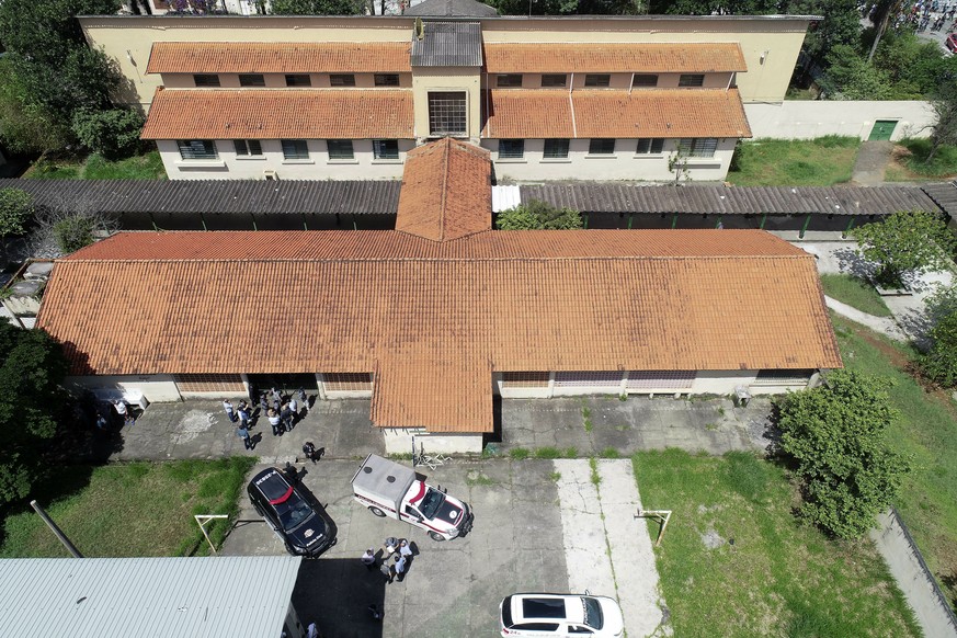 Police officers and investigators stand outside the Raul Brasil State School in Suzano, the greater Sao Paulo area, Brazil, Wednesday, March 13, 2019. The state government of Sao Paulo said two teenag ...