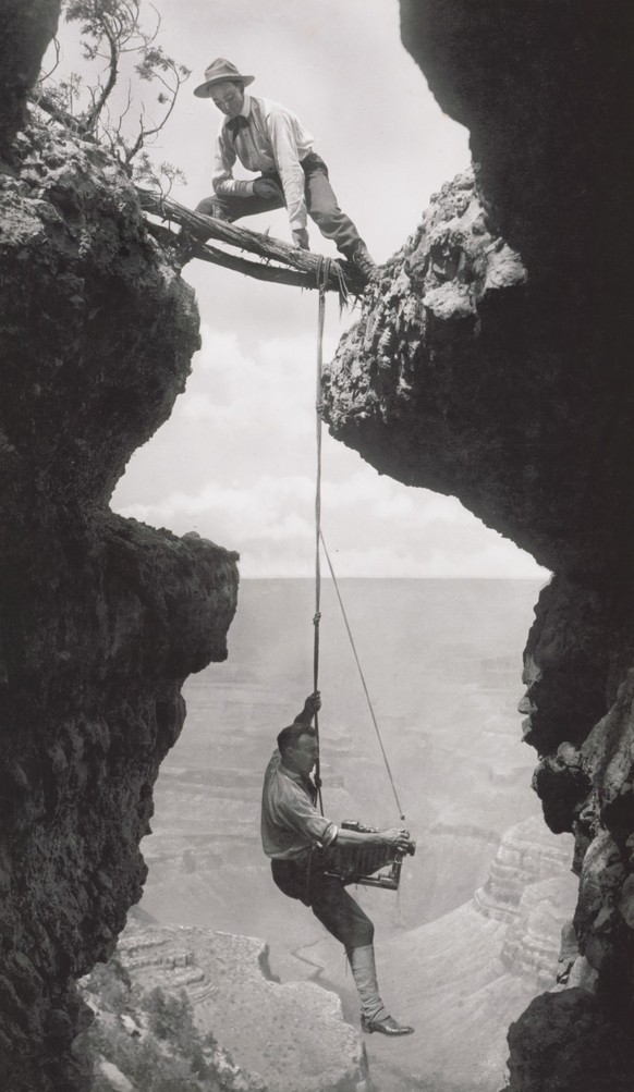 Photographer, Emery or Elsworth Kolb, Suspended on Climbers Rope in Crevasse and Photographing Canyon Wall as Another Man Straddles Cliff Opening while Holding the Rope, Grand Canyon, Arizona, USA, by ...