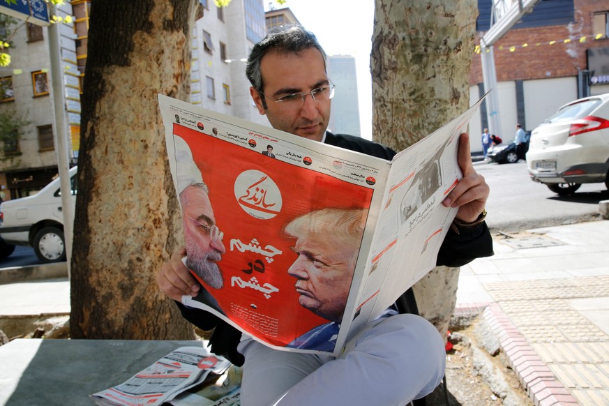 epa07493744 An Iranian man reads the Iranian daily newspaper &#039;Sazandegi&#039; with a pictures of Iranian president Hassan Rouhani and US President Donald Trump on its front page and the title rea ...