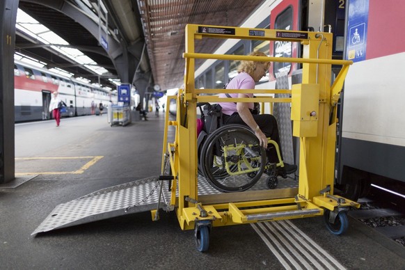A woman in a wheelchair uses a lifting platform at Zurich Main Station to get on an Interregio train to Baden, Switzerland, on August 28, 2014. (KEYSTONE/Gaetan Bally)