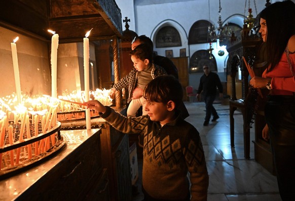 A Palestinian Christian boy lights a candle at the Church of the Nativity, believed to be the birthplace of Jesus, in the biblical city of Bethlehem, West Bank, on Sunday, December 17, 2023.  The church, n...