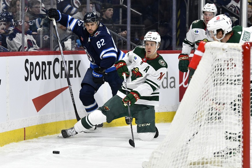 Minnesota Wild&#039;s Joel Eriksson Ek (14) passes the puck behind the net as he is checked by Winnipeg Jets&#039; Nino Niederreiter (62) during the second period of an NHL hockey game Tuesday, Feb. 2 ...