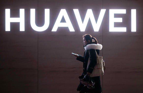 epa11169762 A woman walks past a Huawei logo, in Shanghai, China, 21 February 2024. According to a report published on 21 February by the consulting firm International Data Corporation (IDC), Huawei h ...