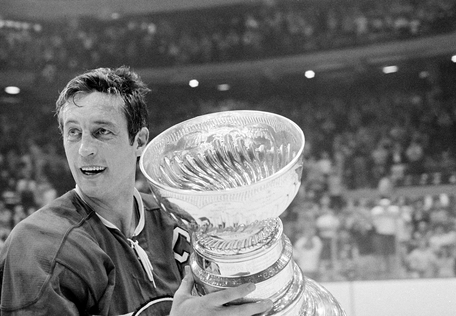 Montreal Canadiens team captain Jean Beliveau holds the Stanley Cup trophy after his team's 3-2 victory over the Chicago Black Hawks in the NHL playoff game in Chicago, Ill., Tuesday night, May 1 ...