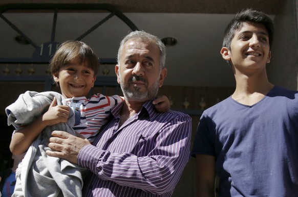 Osama Abdul Mohsen (C), a Syrian refugee who was filmed being tripped up by a camerawoman as he fled police in Hungary with his young son Zaid, poses with Zaid and his other son Mohammad al Ghadabe (R ...