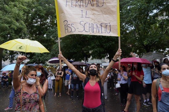 A woman holds up a banner reading in Italian &quot;Let&#039;s stop the slavery-pass&quot; during a protest in Milan, Italy, Saturday, July 24, 2021. Italy&#039;s government approved a decree ordering  ...