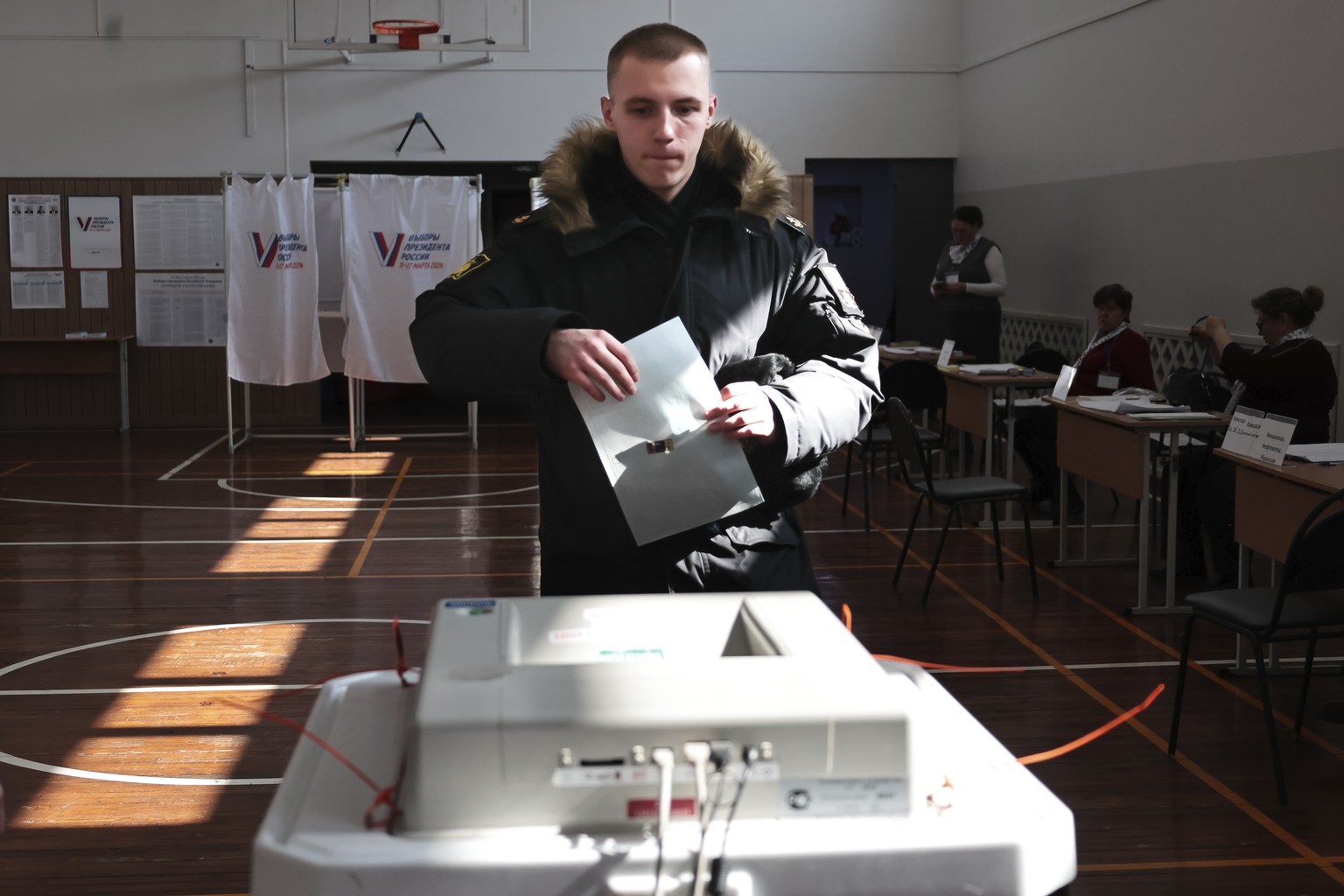 A military cadet prepares to cast a ballot at a pooling station in the Pacific Higher Naval School during a presidential election in the Pacific port city of Vladivostok, east of Moscow, Russia, Frida ...
