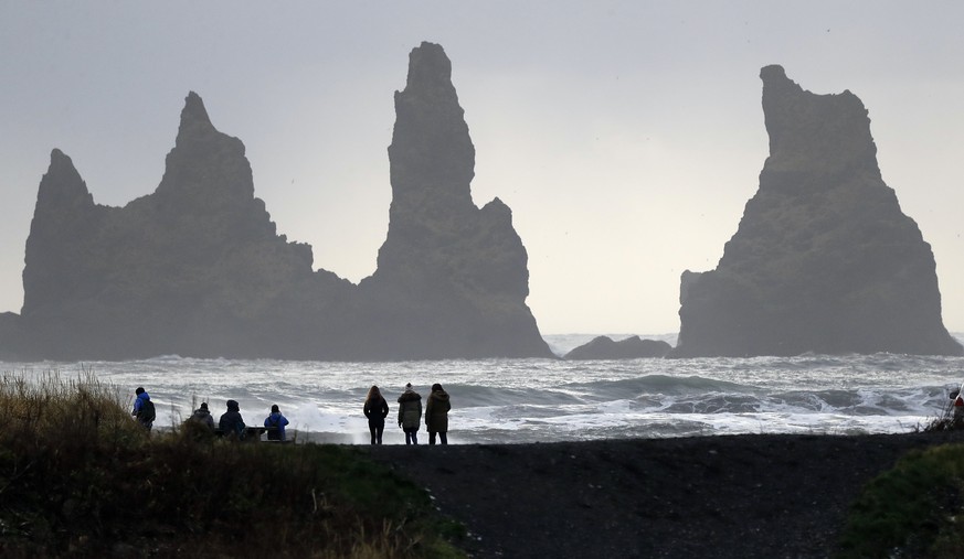 People walk on the black sanded beach in Vik, Iceland, near the Volcano Katla, Wednesday, Oct. 26, 2016. Katla Volcano has helped turn sleepy Vik, a community of 300 people some 110 miles (180 kilomet ...