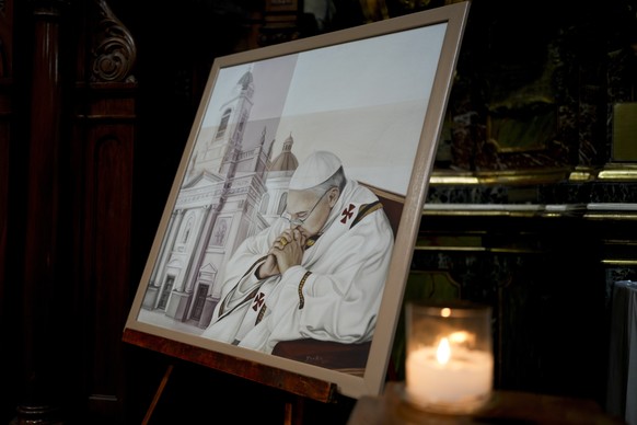 A candle glimmers alongside a painting of Pope Francis at San Jos