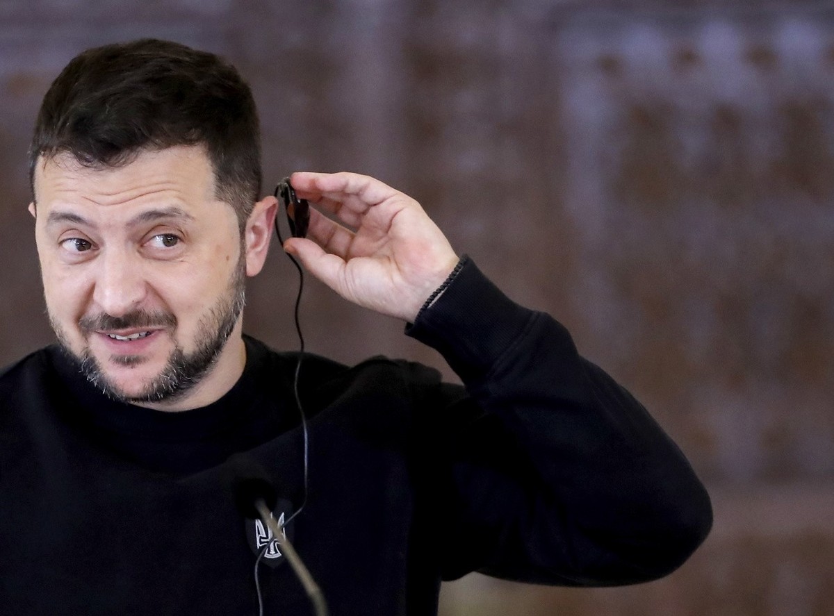 epa10911128 Ukrainian President Volodymyr Zelensky adjusts his earpiece during a press conference with Romanian President Klaus Iohannis (not pictured) after their meeting at the Cotroceni Palace, in  ...