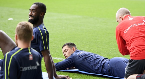 Switzerland&#039;s midfielder Granit Xhaka, center, is warming up by physiotherapists next to Johan Djourou , left, before a training session on the eve of an international friendly soccer match betwe ...