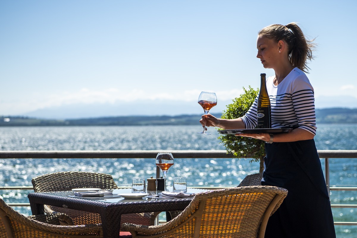 Une femme sert un verre de vin sur la terrasse de l'Hotel Palafitte construit sur pilotis au-dessus du lac de Neuchatel lors de la crise du Coronavirus (Covid-19) le vendredi 29 mai 2020 a Neucha ...