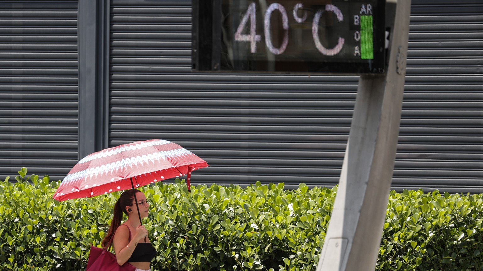 epa10975080 A young woman protects herself from the sun with an umbrella on Paulista Avenue, where urban thermometers record a temperature of 40.0 degrees Celsius in the city of Sao Paulo, Brazil, 1...