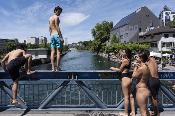Feriengaeste aus Barcelona springen vom Drahtschmidlisteg in die Limmat, fotografiert am Sonntag, 14. Juli 2024 in Zuerich. (KEYSTONE/Gaetan Bally)