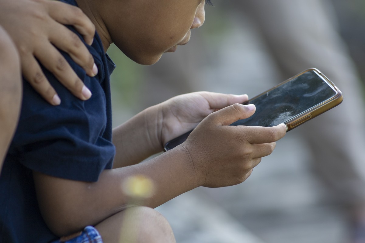 epa12855803 A child uses a mobile phone at a park in Denpasar, Bali, Indonesia, 28 March 2026. The Indonesian government implemented a regulation restricting social media use for children under the ag ...