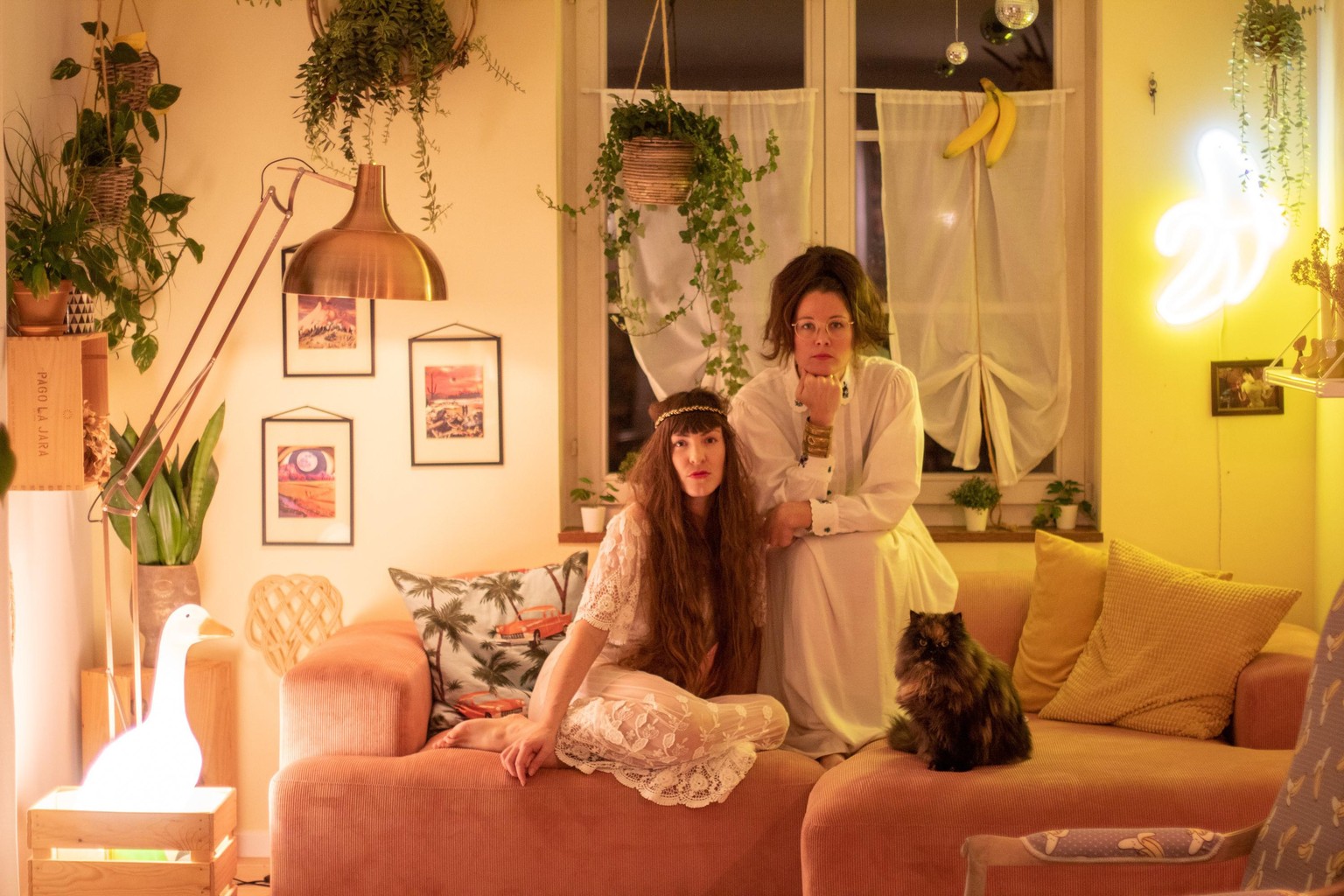 Die zwei Sektologinnen Anna Hugo und Francesca Stamm mit der Orakelkatze Ivan Klepturion auf dem Sofa der Erkenntnis.