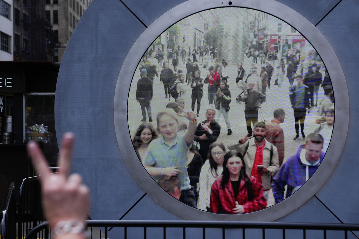People in both New York and Dublin, Ireland, wave and signal at each other while looking at a livestream view of one another as part of an art installation on the street in New York, Tuesday, May 14,  ...