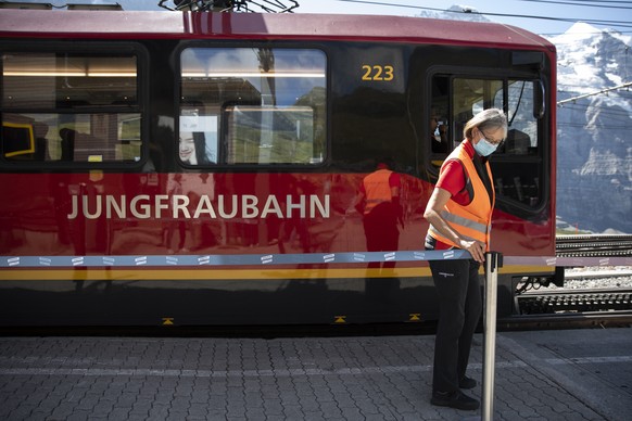 Eine Mitarbeiterin der Jungfraubahnen schliesst einen Durchgang auf der kleinen Scheidegg, am Samstag, 15. August 2020. (KEYSTONE/Peter Klaunzer)