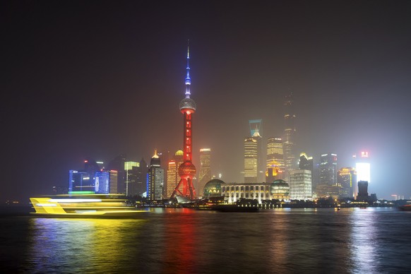 A ferry travels past the Oriental Pearl Tower, lit in the colors of the French flag in Shanghai, China, Saturday, Nov. 14, 2015, following the attacks in Paris on Friday. French President Francois Hol ...