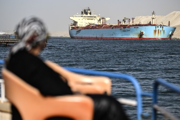 epa11040958 A person watches as a ship crosses the Suez Canal towards the Red Sea in Ismailia, Egypt, 22 December 2023. On 18 December, the US Department of Defense announced a multinational operation ...