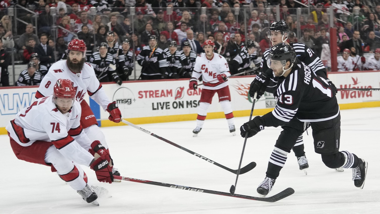 New Jersey Devils center Nico Hischier (13) shoots the puck to score past Carolina Hurricanes defenseman Jaccob Slavin (74) during the second period of an NHL hockey game, Saturday, March 9, 2024, in  ...