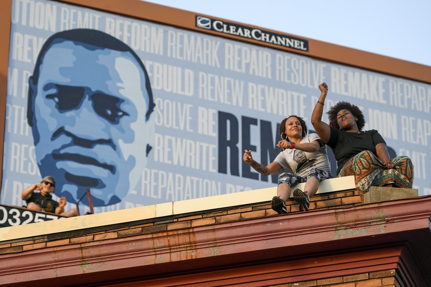 epaselect epa09228183 Two women sit on the roof of Cup Foods and listen to the music performed at George Floyd&#039;s Square as hundreds gather at 38th Street and Chicago Ave., the sight where Floyd w ...