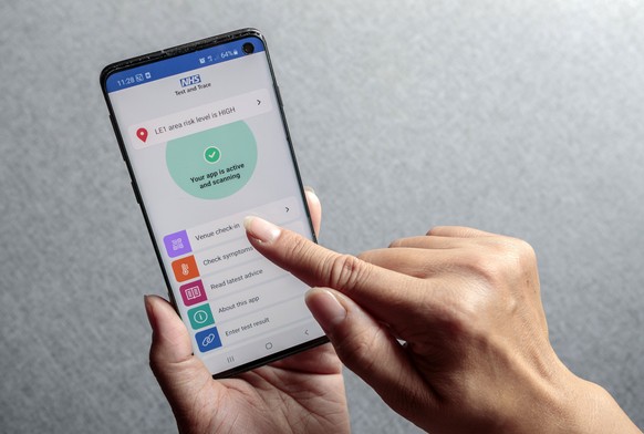 A woman poses for a photo using the new NHS COVID-19 mobile phone application after the app went live on Thursday morning, in Leeds, England, Thursday, Sept. 24, 2020. The rollout follows months of de ...