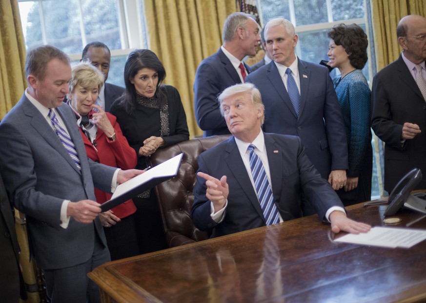 President Donald Trump looks over towards Budget Director Mick Mulvaney, left, after signing an executive order in the Oval Office of the White House in Washington, Monday, March 13, 2017. Trump signe ...