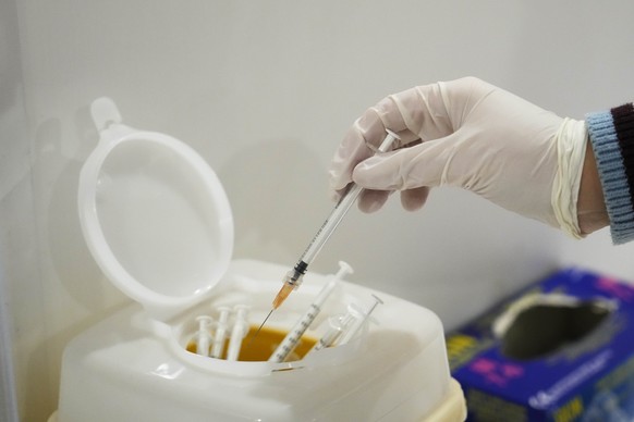 A nurse puts a used syringe into a box at an Italian Red Cross anti COVID-19 vaccination hub, in Rome, Monday, Nov. 29, 2021. Italy was reinforcing checks at borders and going through lists of airline ...