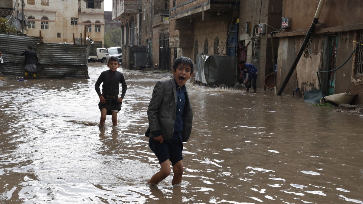 epa10101773 Yemenis wade through a flooded street following a heavy rainfall in Sana'a, Yemen, 01 August 2022. Torrential rains and associated floods have hit several areas of Yemen, including th ...
