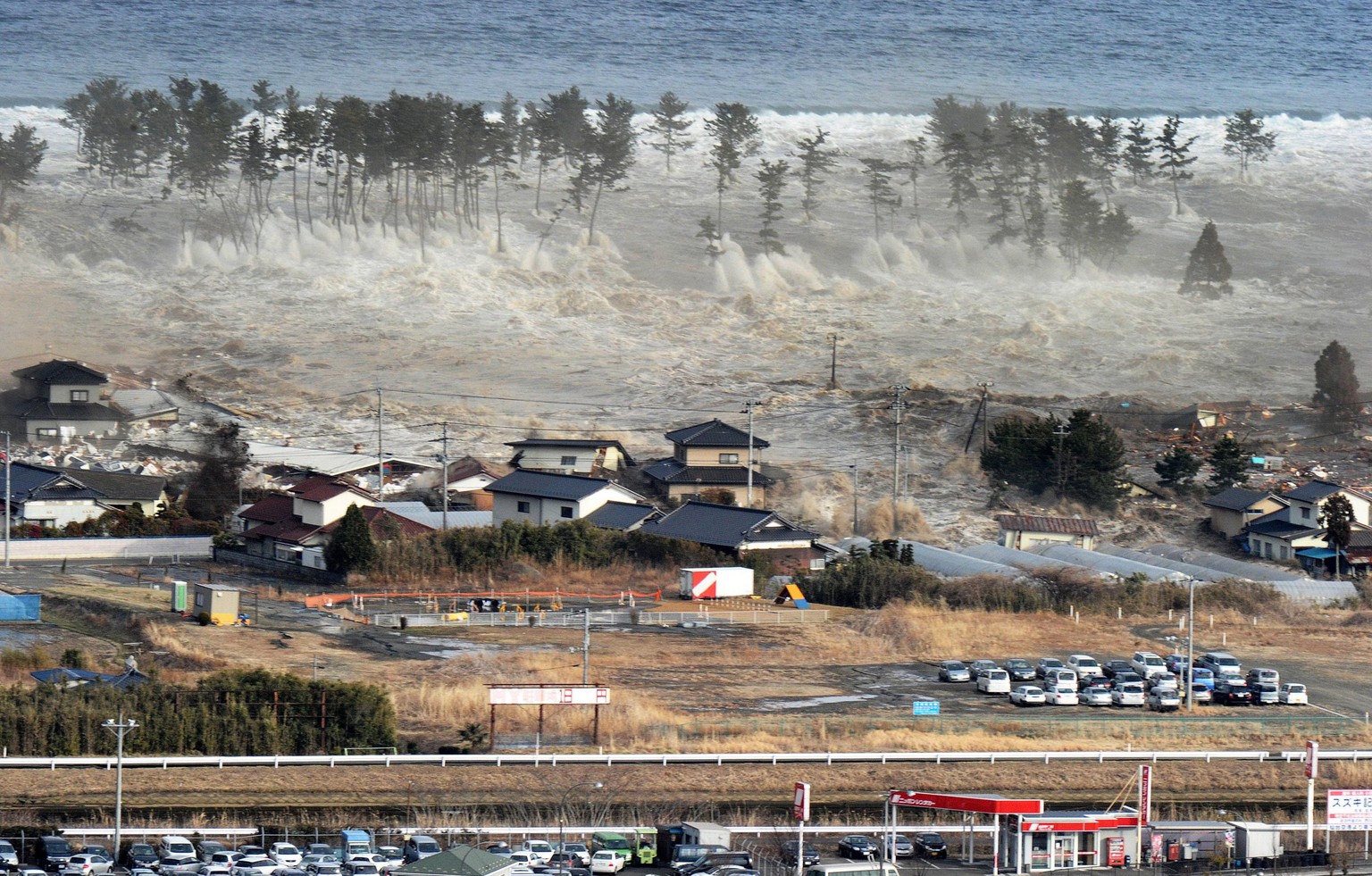 Eine Aufnahme vom 11. März 2011 zeigt, wie die Tsunami-Flutwelle unzählige Häuser mit sich reisst.