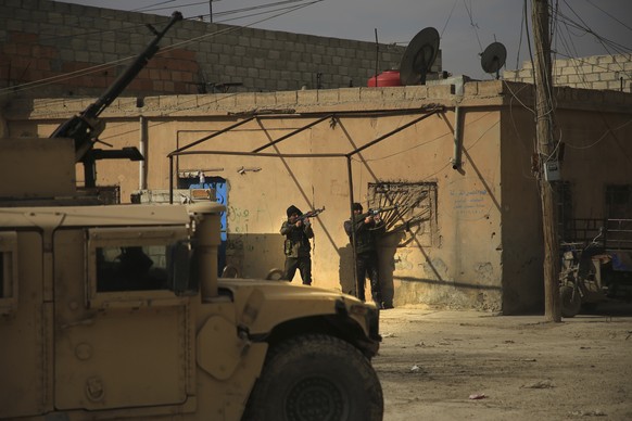 Kurdish-led Syrian Democratic Forces fighters, take their positions at an alley near Gweiran Prison, in Hassakeh, northeast Syria, Sunday, Jan. 23, 2022. Clashes between U.S.-backed Syrian Kurdish fig ...