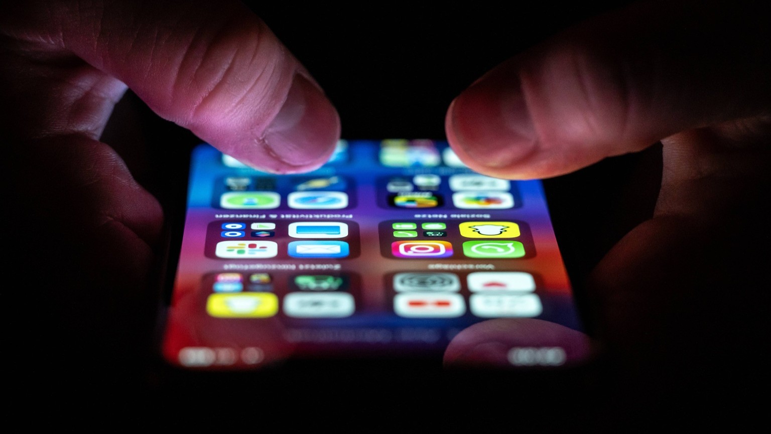 Eine Frau bedient ein iPhone auf dem zahlreiche Applikation Apps installiert sind.