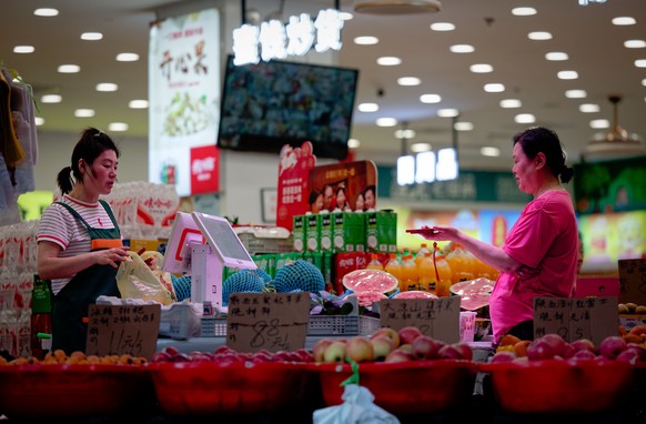 epaselect epa12947274 A woman buys groceries at a shop in Shanghai, China, 11 May 2026. The National Bureau of Statistics of China reported that annual inflation rose to 1.2 percent in April 2026, up  ...