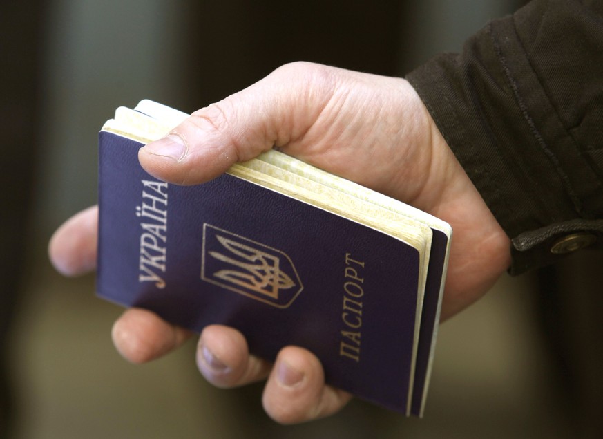 A man holds Ukranian passports as he queues to apply for Russian passports at a passport office in Sevastopol March 24, 2014. Ukraine announced the evacuation of its troops and their families from Cri ...
