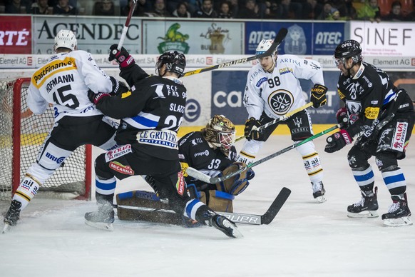 Freiburgs Goalie Barry Brust und Freiburgs Jim Slater, 2.v.l., gegen Luganos Gregory Hofmann, links, waehrend dem Eishockey-Meisterschaftsspiel der National League zwischen dem HC Fribourg Gotteron un ...